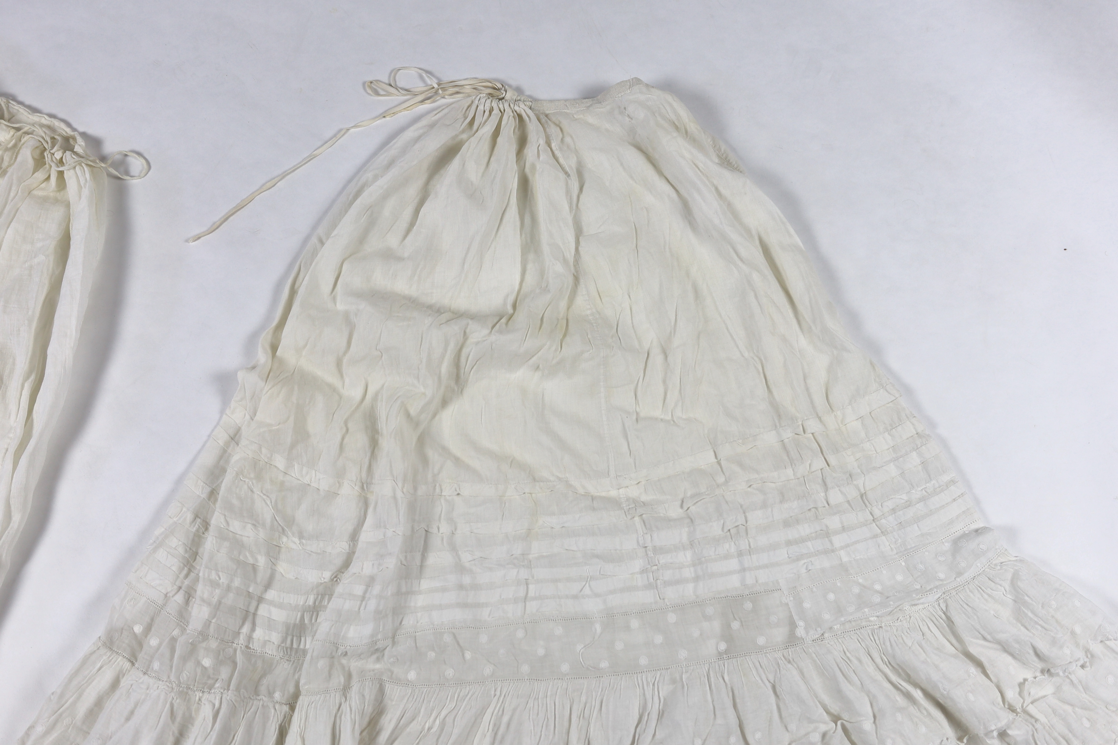 Three Victorian white worked petticoats; one two tiered, one lace trimmed with ribboning, the third worked with cutwork border, all approx. 94cm long